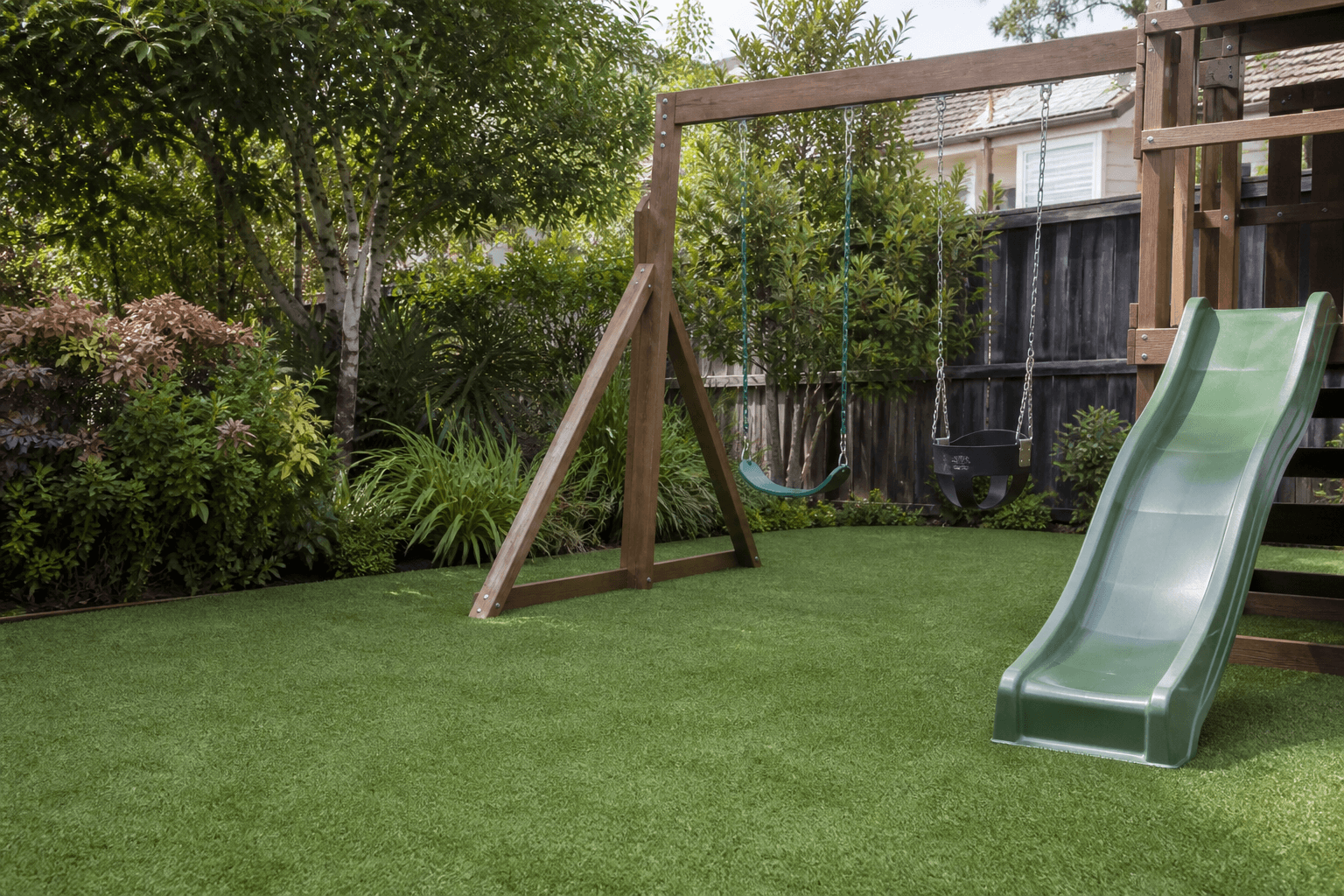 Soft artificial playground turf under a wooden backyard swing set and slide in Surrey